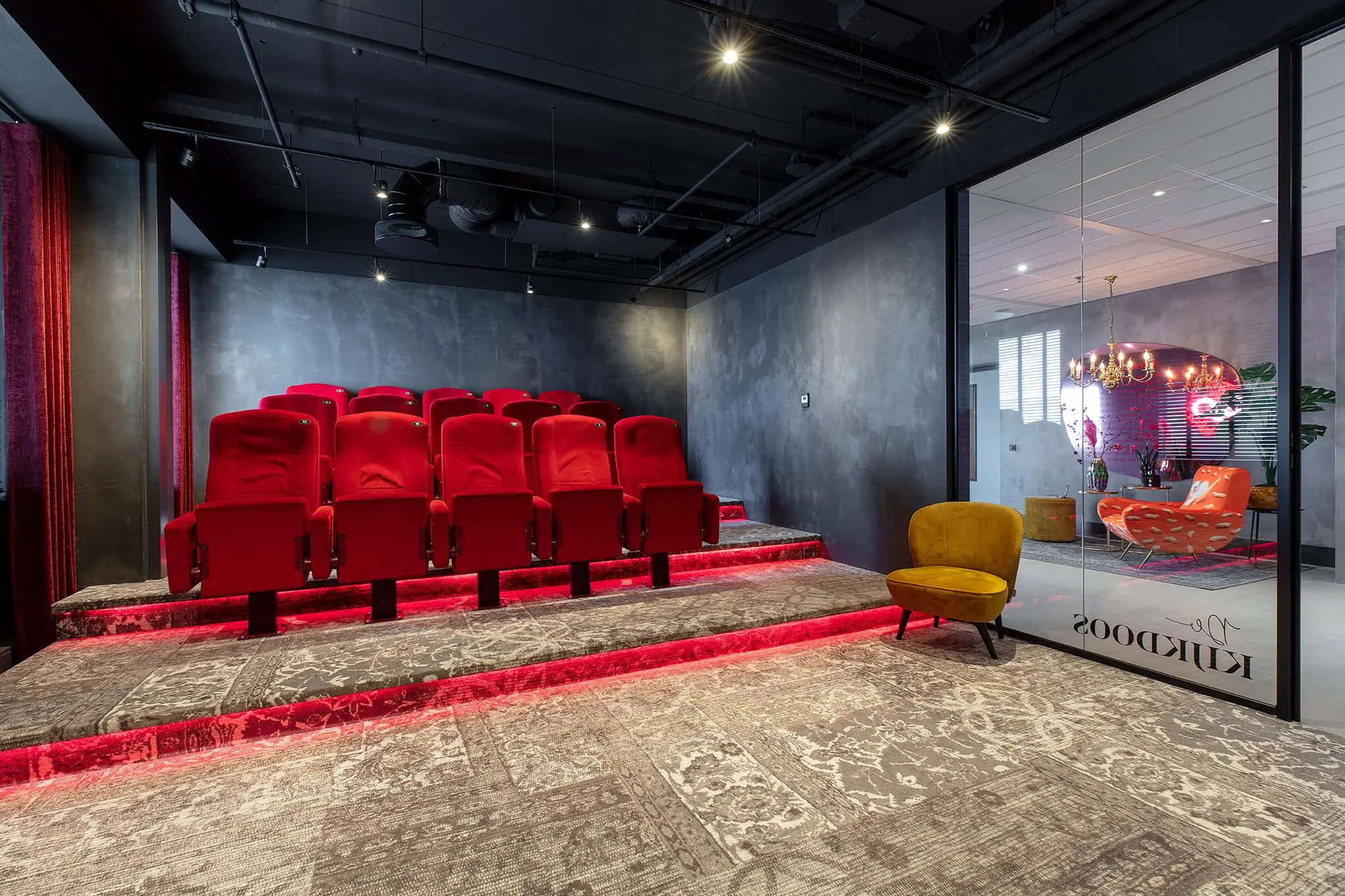 Moderne, sfeervol verlichte privébioscoop met rode stoelen in een ruimte aan de Vliegend Hertlaan.